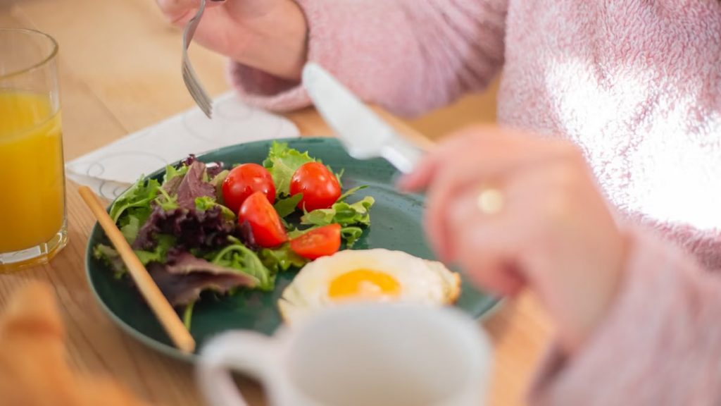 Enjoy a nutritious breakfast with greens, fried egg, and fresh orange juice for a healthy start to your day.